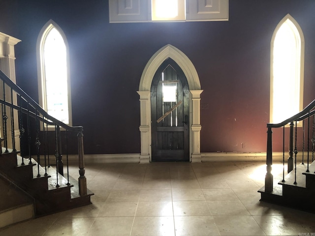 foyer entrance featuring arched walkways, a wealth of natural light, and stairs
