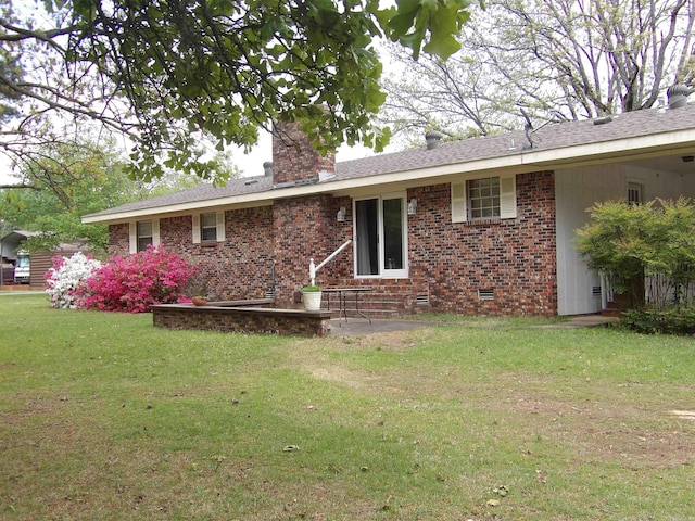 exterior space featuring crawl space, a chimney, brick siding, and a yard