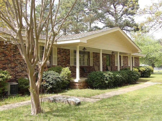 view of side of property featuring a porch, brick siding, a yard, and cooling unit
