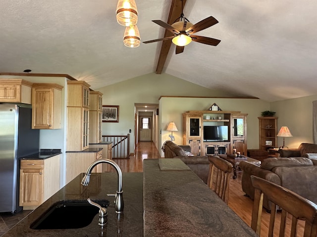 kitchen with light brown cabinetry, open floor plan, a ceiling fan, and a sink