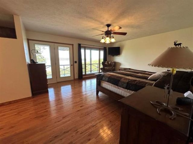 bedroom with a textured ceiling, ceiling fan, french doors, access to exterior, and wood finished floors