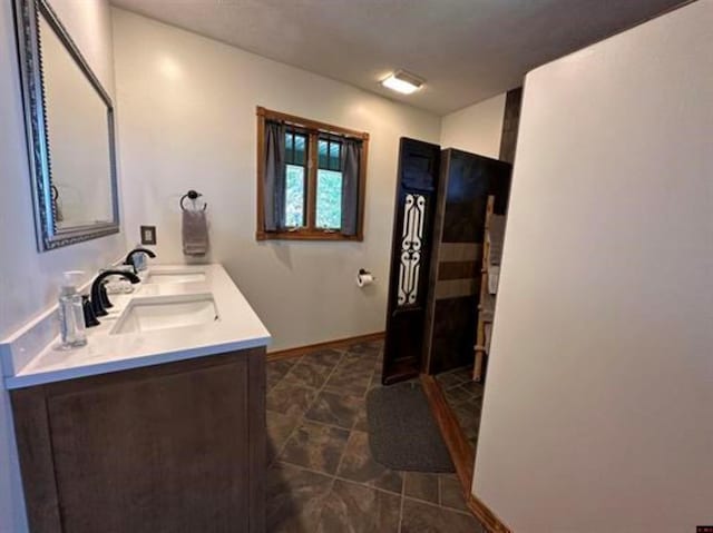 bathroom featuring a sink, double vanity, tile patterned floors, and baseboards