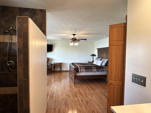 bedroom with a textured ceiling, ceiling fan, and wood finished floors