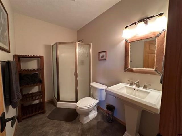 bathroom with baseboards, a shower stall, toilet, and vaulted ceiling