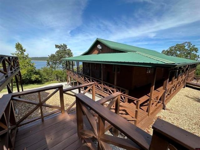 exterior space with a deck with water view and metal roof