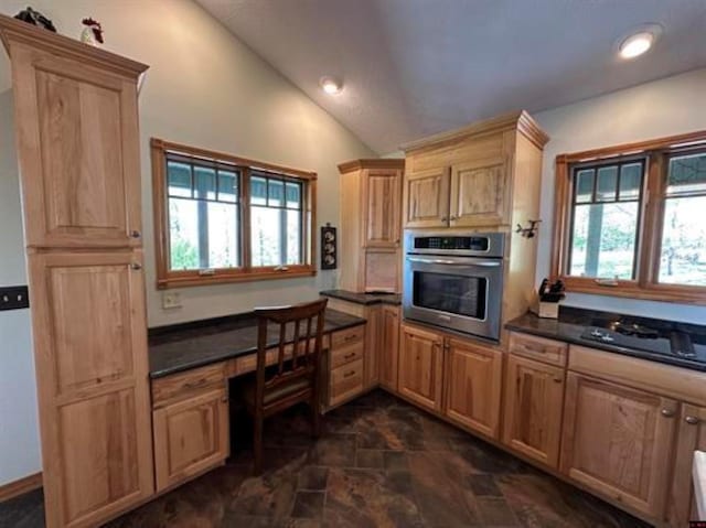 kitchen featuring stone finish flooring, dark countertops, stainless steel oven, and vaulted ceiling