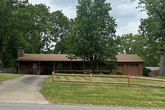 single story home with driveway, a chimney, a garage, fence private yard, and a front yard
