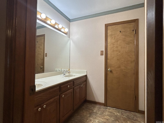 bathroom featuring baseboards, a sink, double vanity, and crown molding