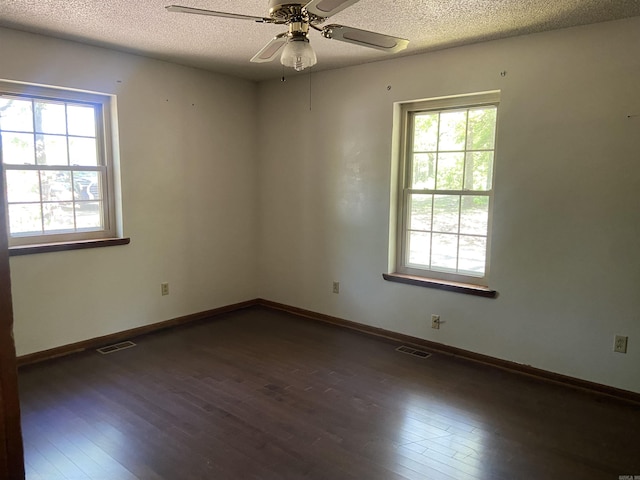 empty room with dark wood-type flooring, visible vents, and plenty of natural light
