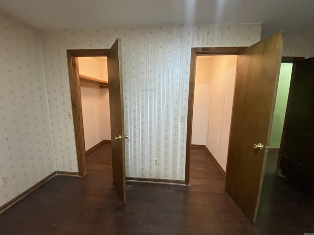 interior space with baseboards, wood finished floors, and wallpapered walls