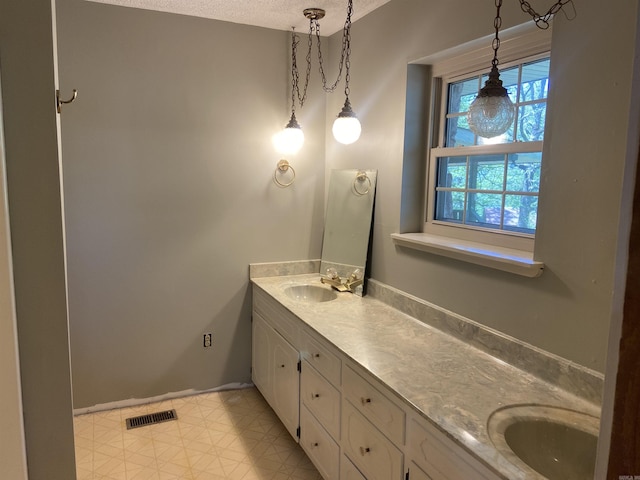 bathroom featuring double vanity, a textured ceiling, baseboards, and a sink