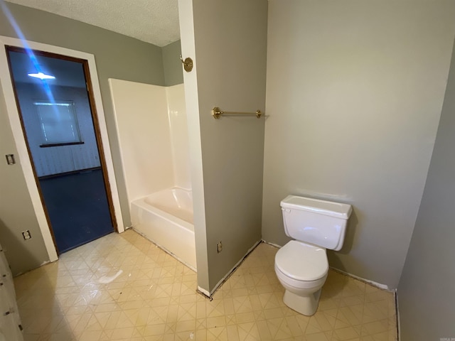 full bath featuring baseboards, washtub / shower combination, and toilet