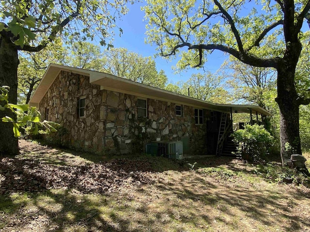 view of side of property featuring stone siding and central AC unit