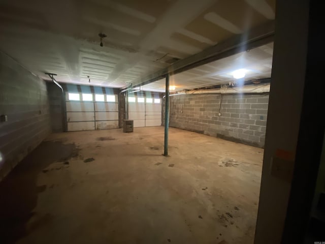 basement featuring concrete block wall and a garage