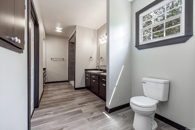 full bathroom with toilet, vanity, wood finished floors, and baseboards