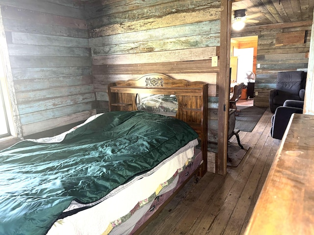 bedroom with hardwood / wood-style floors and wood walls
