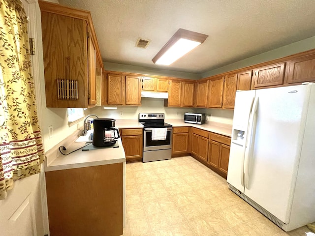 kitchen featuring a sink, brown cabinetry, appliances with stainless steel finishes, under cabinet range hood, and visible vents