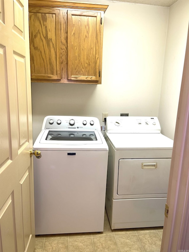laundry room with cabinet space, washing machine and clothes dryer, and light tile patterned flooring