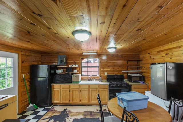 kitchen featuring a sink, light floors, wood ceiling, wooden walls, and black appliances