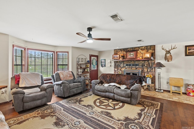 living area with a fireplace, wood-type flooring, visible vents, and a ceiling fan