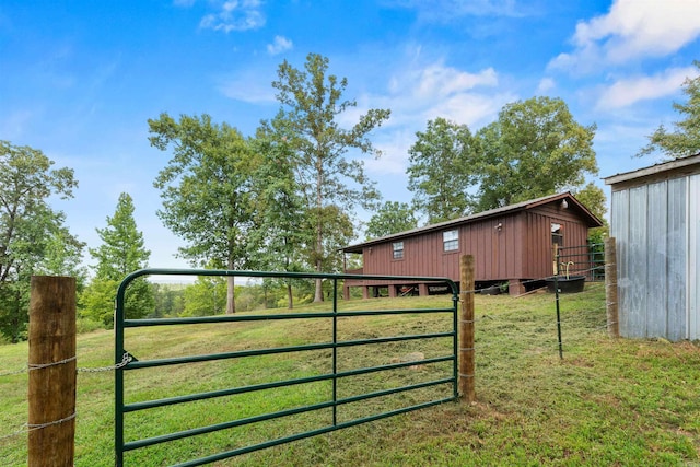 view of gate with a lawn and an outdoor structure