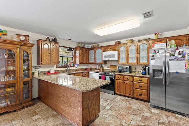 kitchen with visible vents, a sink, a peninsula, brown cabinetry, and appliances with stainless steel finishes
