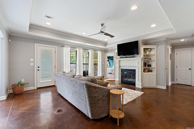 living area with a tray ceiling, a fireplace, a ceiling fan, and visible vents