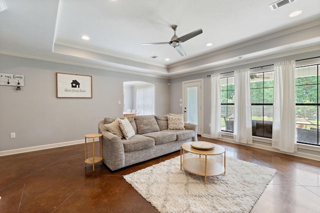living area with arched walkways, crown molding, visible vents, and a raised ceiling