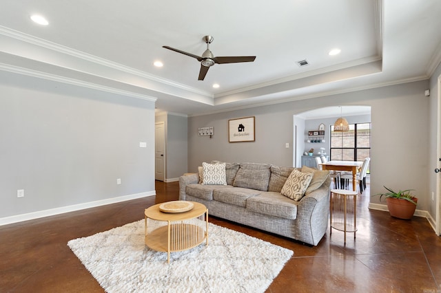 living area with ceiling fan, concrete flooring, a tray ceiling, and baseboards