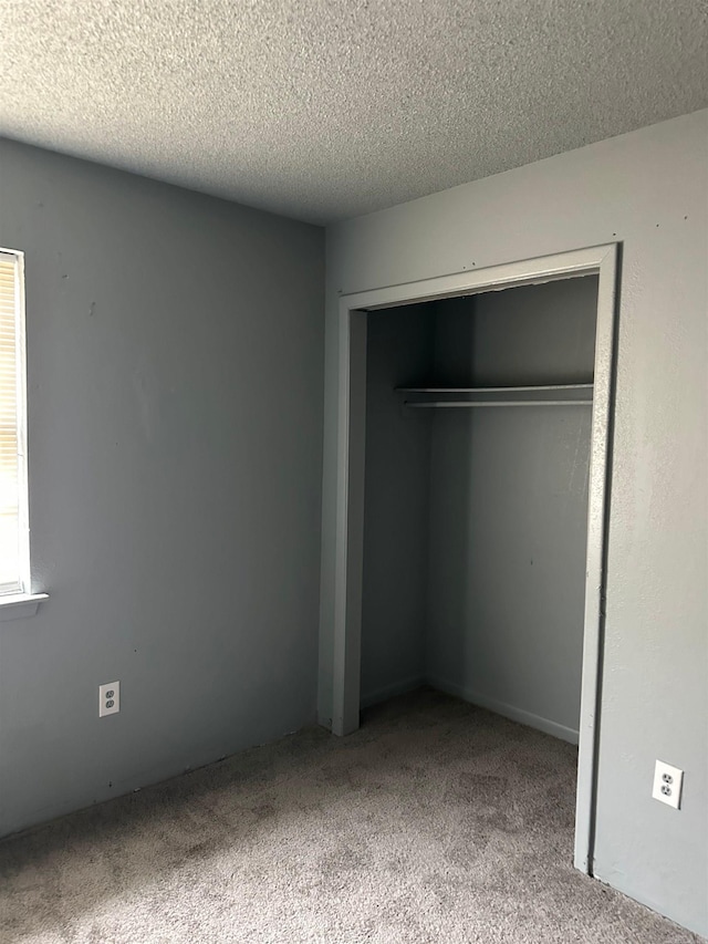 unfurnished bedroom with carpet floors, a textured ceiling, and a closet