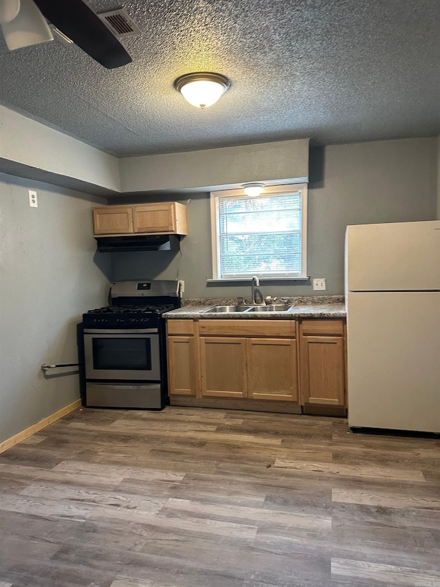 kitchen featuring visible vents, stainless steel range with gas stovetop, a sink, freestanding refrigerator, and light wood-style floors