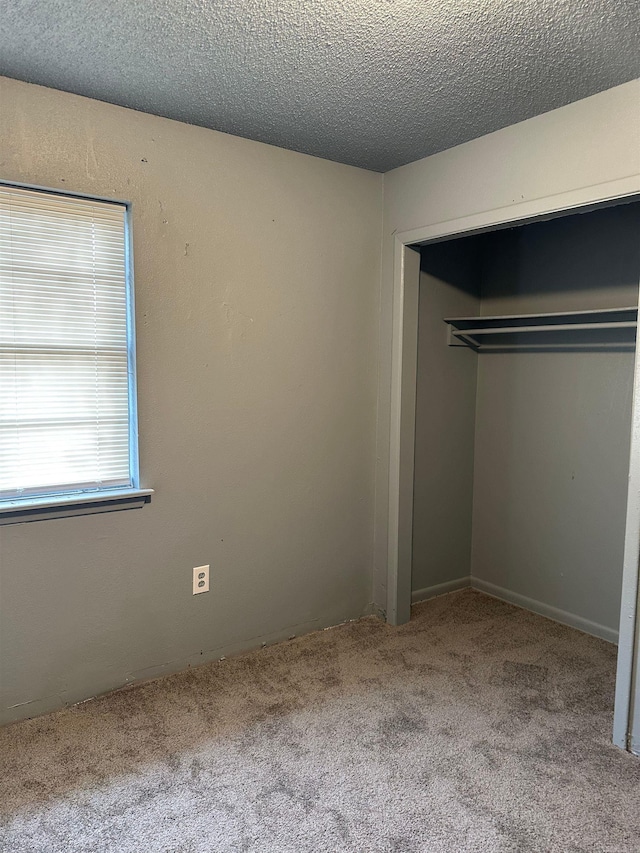 unfurnished bedroom featuring carpet flooring, a textured ceiling, and a closet