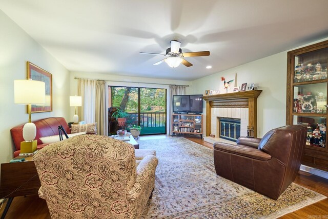 living area with a fireplace, wood finished floors, and a ceiling fan