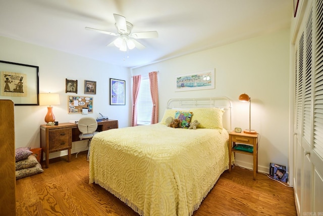 bedroom with ceiling fan, wood finished floors, and a closet
