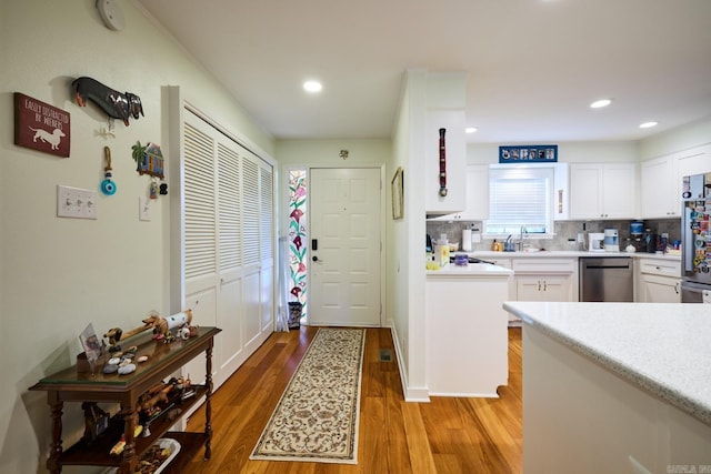 kitchen featuring decorative backsplash, light wood-type flooring, light countertops, white cabinets, and appliances with stainless steel finishes