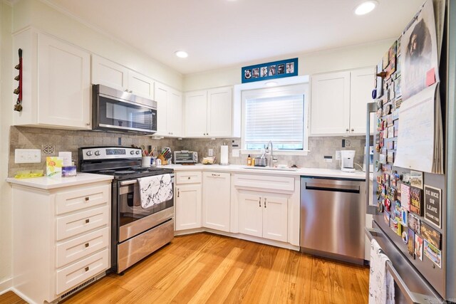 kitchen with light countertops, light wood-style flooring, appliances with stainless steel finishes, and a sink