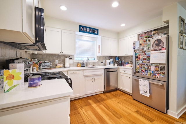 kitchen with light wood-type flooring, stainless steel appliances, white cabinets, and a sink