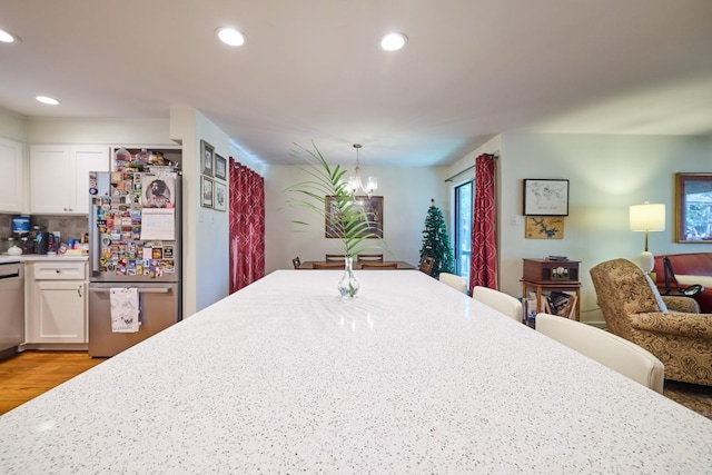 kitchen featuring white cabinets, freestanding refrigerator, decorative backsplash, and recessed lighting