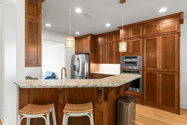 kitchen with stainless steel appliances, a peninsula, light wood-type flooring, visible vents, and brown cabinetry