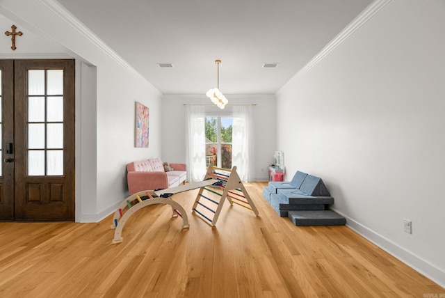 sitting room featuring light wood-type flooring, visible vents, baseboards, and ornamental molding