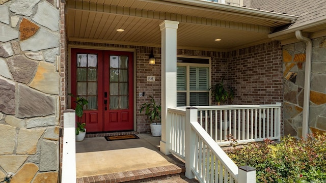 property entrance with covered porch, french doors, and brick siding