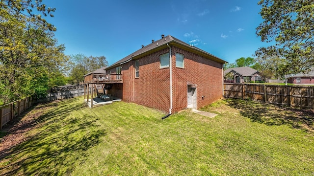 back of property featuring a fenced backyard, a wooden deck, brick siding, and a yard