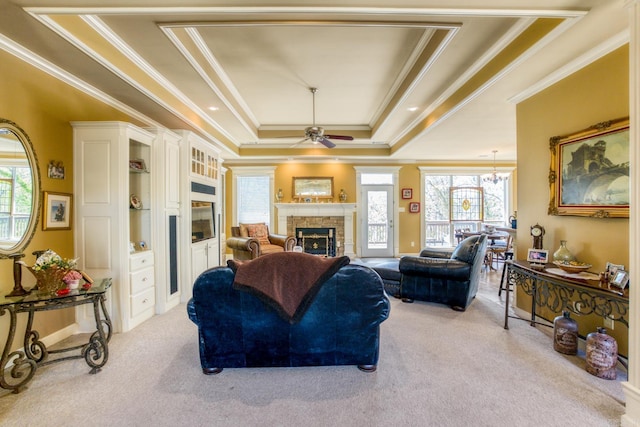 living area featuring a tray ceiling, plenty of natural light, a fireplace, and light carpet
