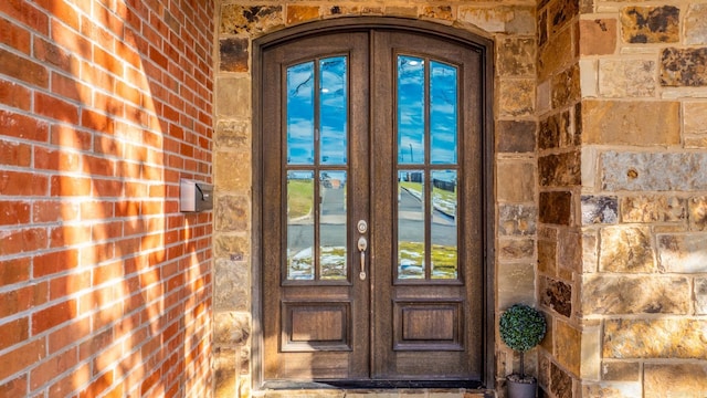 entrance to property featuring brick siding and french doors