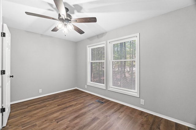 unfurnished room featuring baseboards, visible vents, dark wood-style floors, and ceiling fan