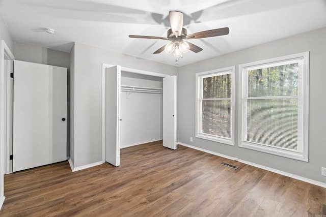 unfurnished bedroom with baseboards, wood finished floors, visible vents, and a closet