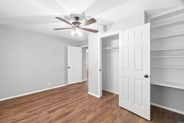 unfurnished bedroom with baseboards, a ceiling fan, wood finished floors, and two closets