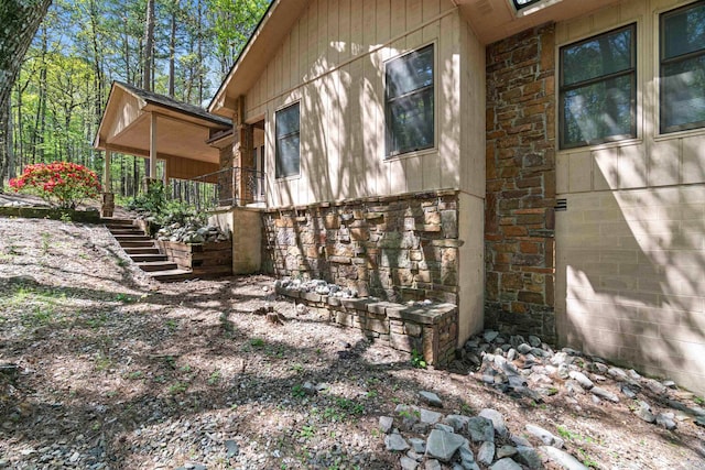 view of side of property with stone siding and stairs