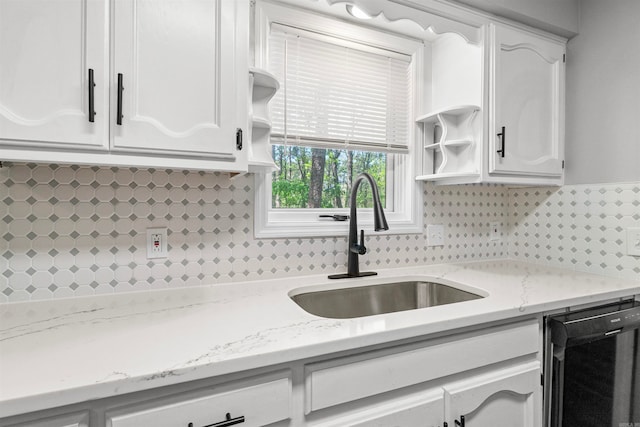 kitchen featuring white cabinetry, open shelves, black dishwasher, and a sink