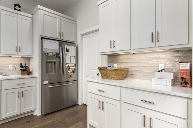 kitchen featuring decorative backsplash, stainless steel fridge with ice dispenser, white cabinets, light stone countertops, and dark wood-type flooring
